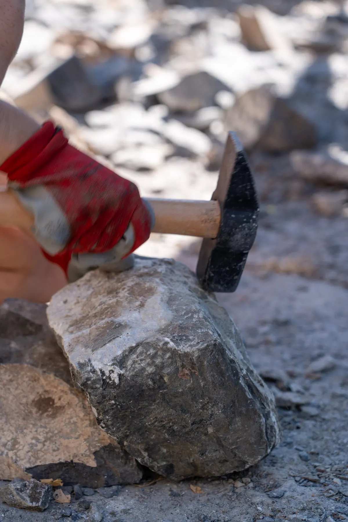 A gloved hand steadying a stone under the hammer